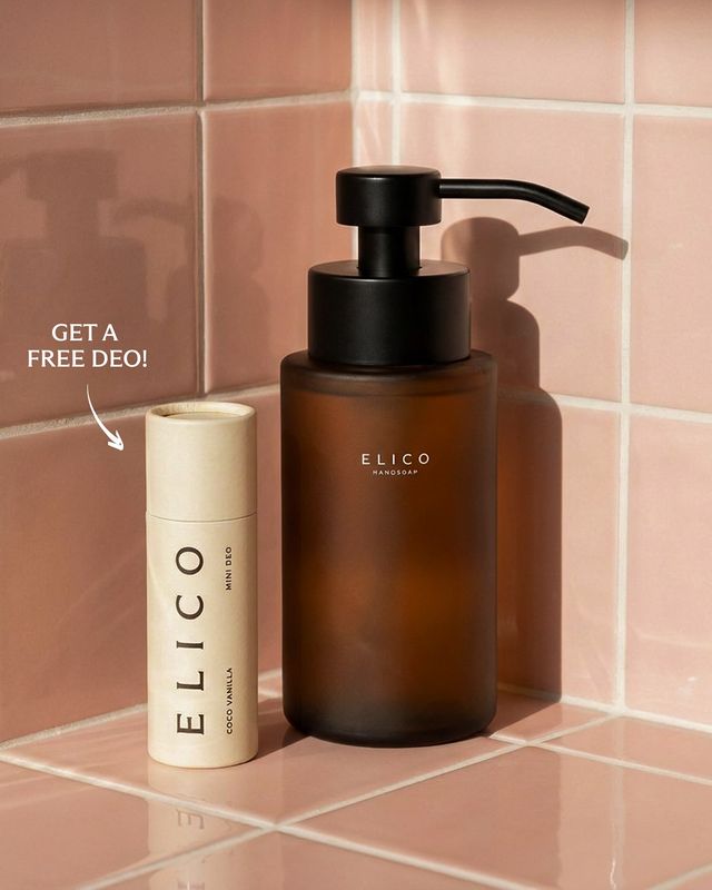 Dispenser i bärnstensglas och en mini deo mot rosa kakel
