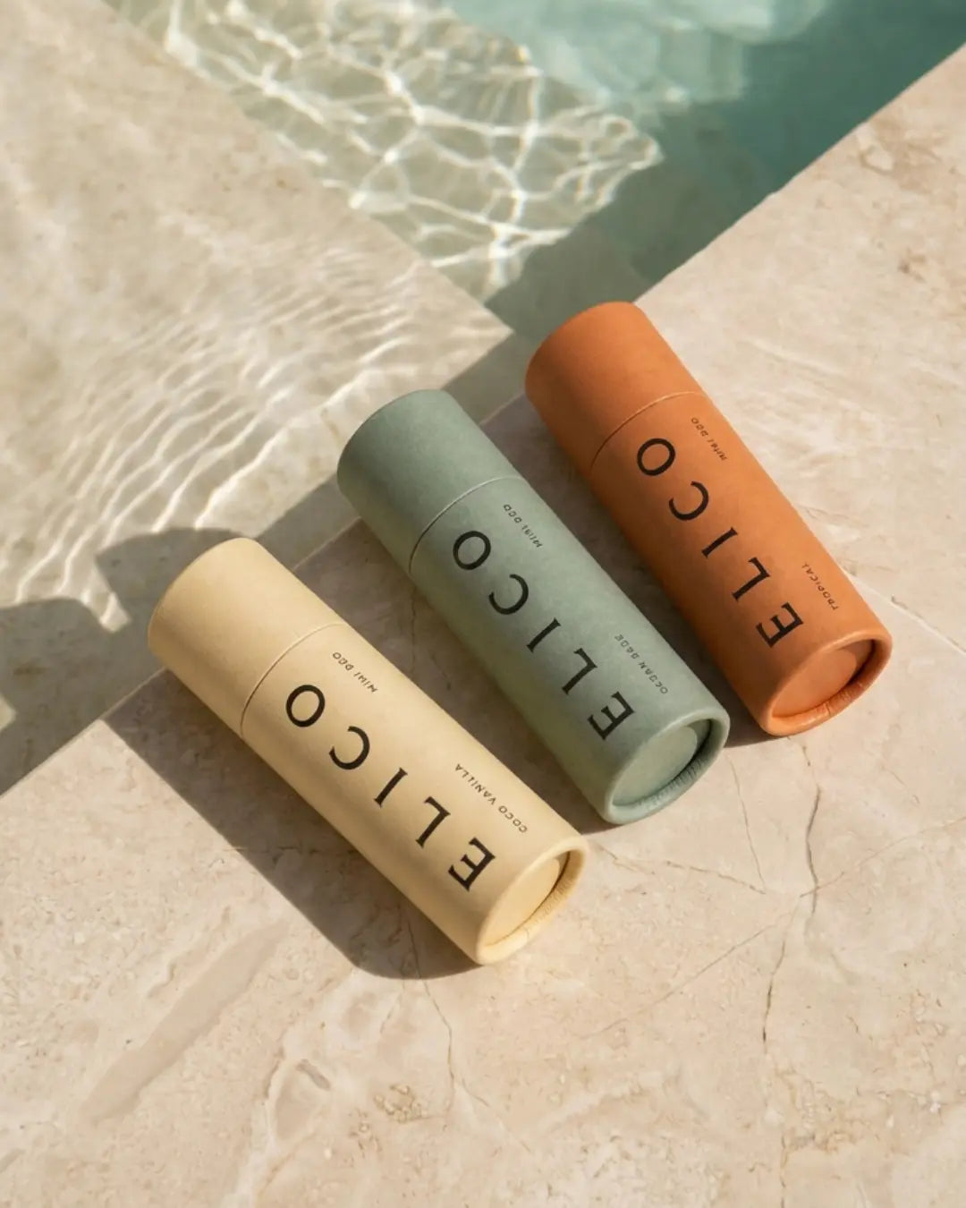 Three Mini Deo tubes in sunlight at the edge of a pool